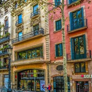 A city street with terraced buildings containing shops, restaurants and flats.